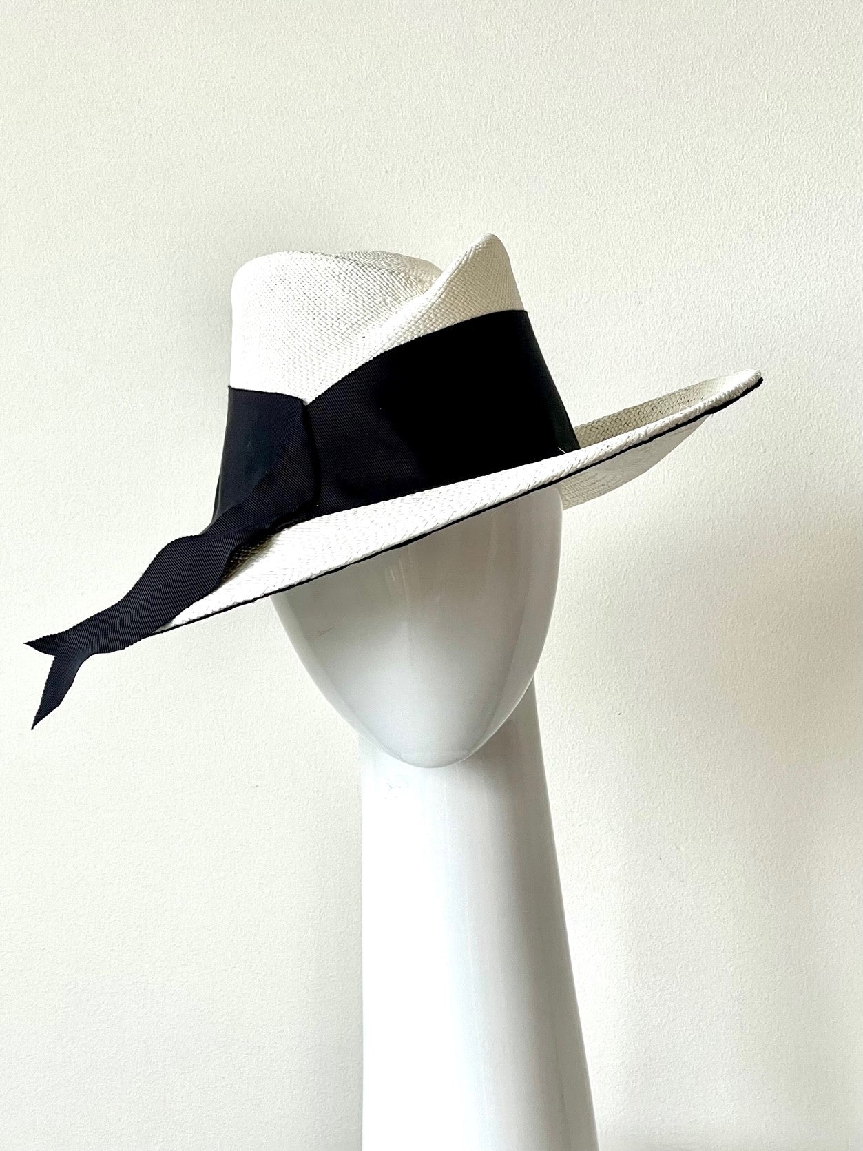The White Panama Fedora with Black Trim is a modern fedora with a sweeping angular crown and features a wide brim which softly curves up.