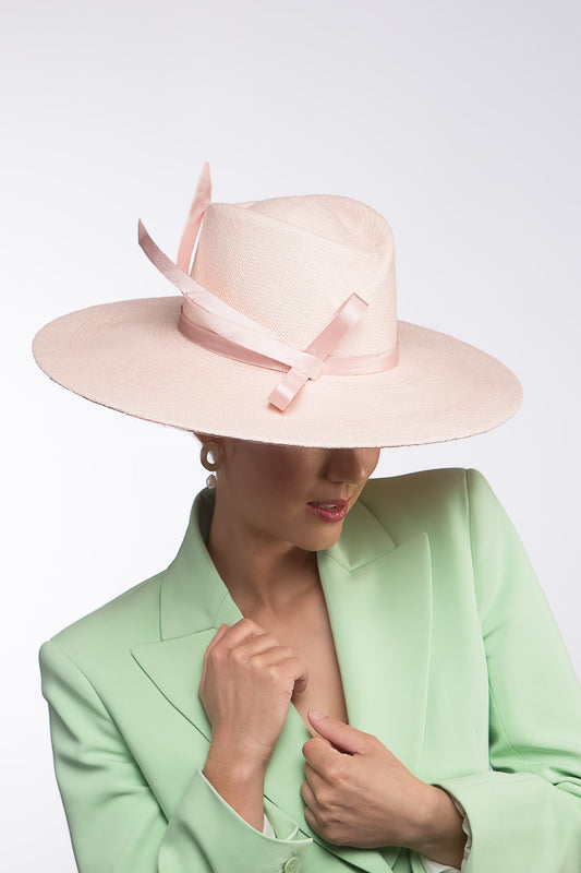 The Pink Panama Fedora with Silk Bow is a modern fedora with a sweeping angular crown and a wide flat brim in pastel pink straw