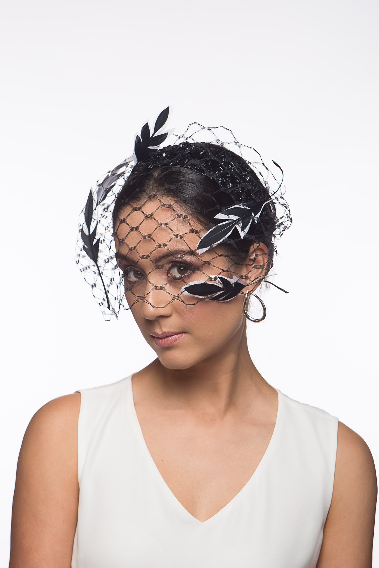 The Veiled Feather Leaf Headband in Black and White features a birdcage veil adorned with feather leave