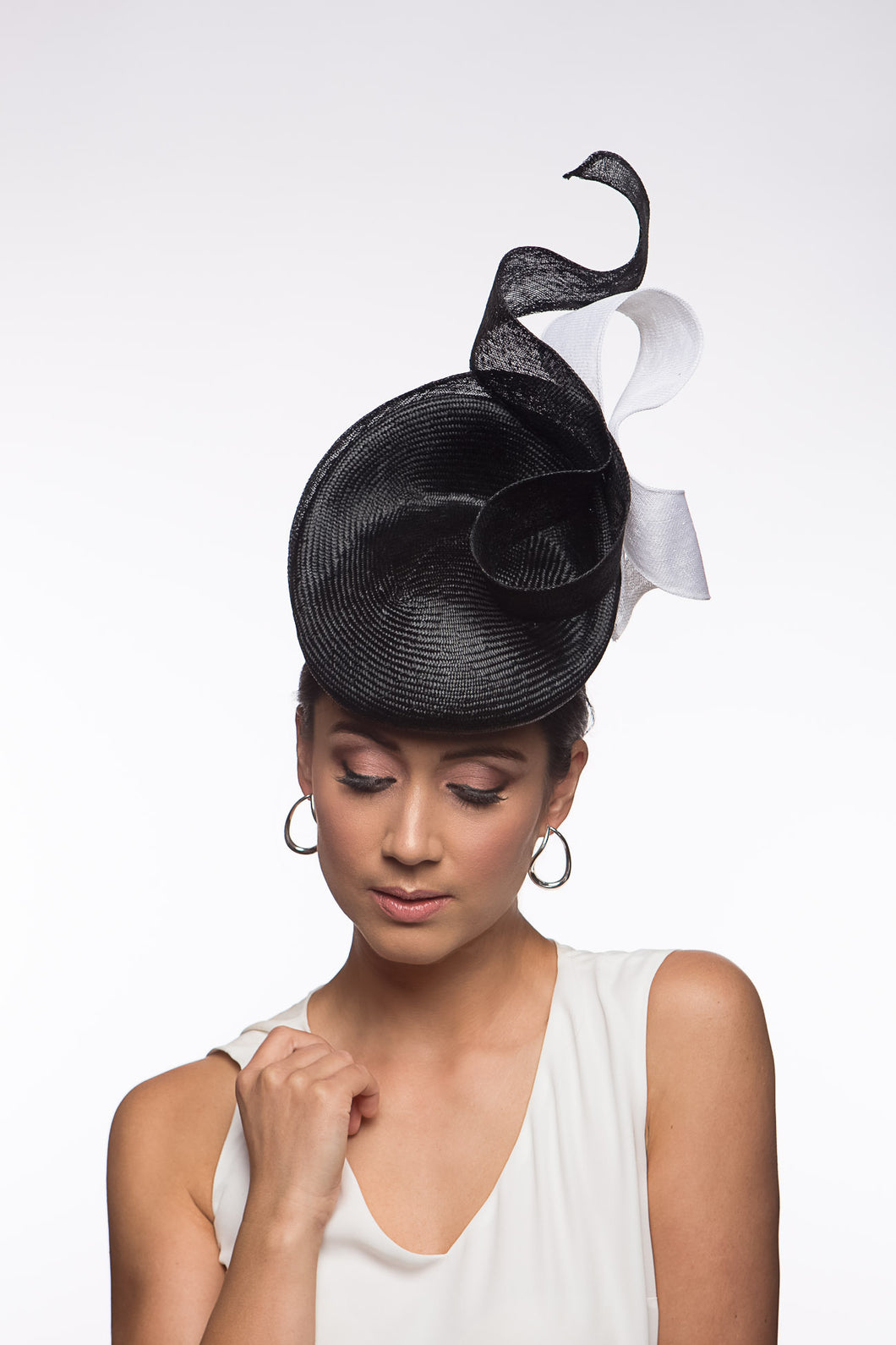 The Black and White Swirl Beret Platter Hat is a, raised button beret in black straw and trimmed with a white floating bow