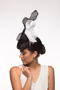 The Black and White Swirl Beret Platter Hat is a, raised button beret in black straw and trimmed with a white floating bow