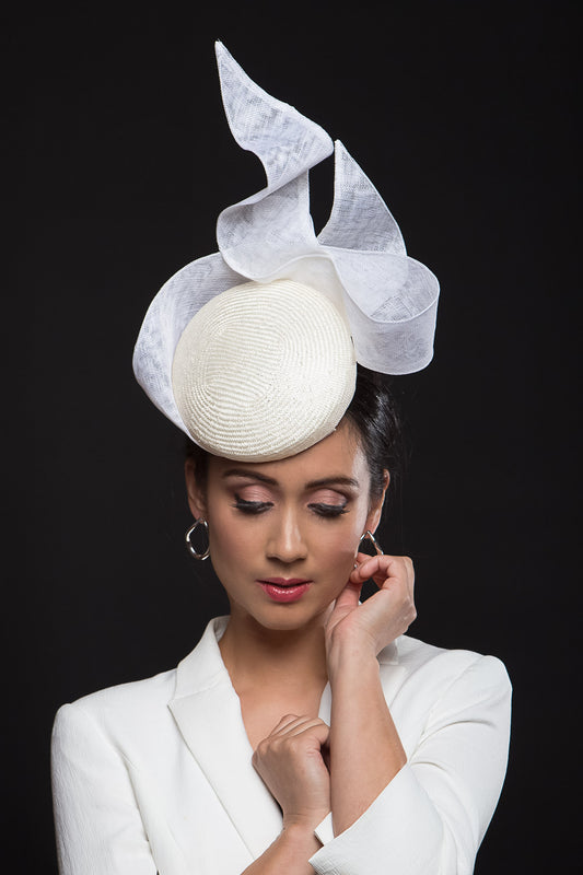 he Ivory and White Swirl Cocktail Hat is a beautiful, raised button beret in ivory straw and trimmed with a gorgeous white floating bow that adds lightness and height