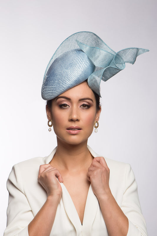 The Pale Blue Sculptured Beret style is an oval side beret Trimmed with curls of sinamay. Buy this millinery online or make an appointment to try it on