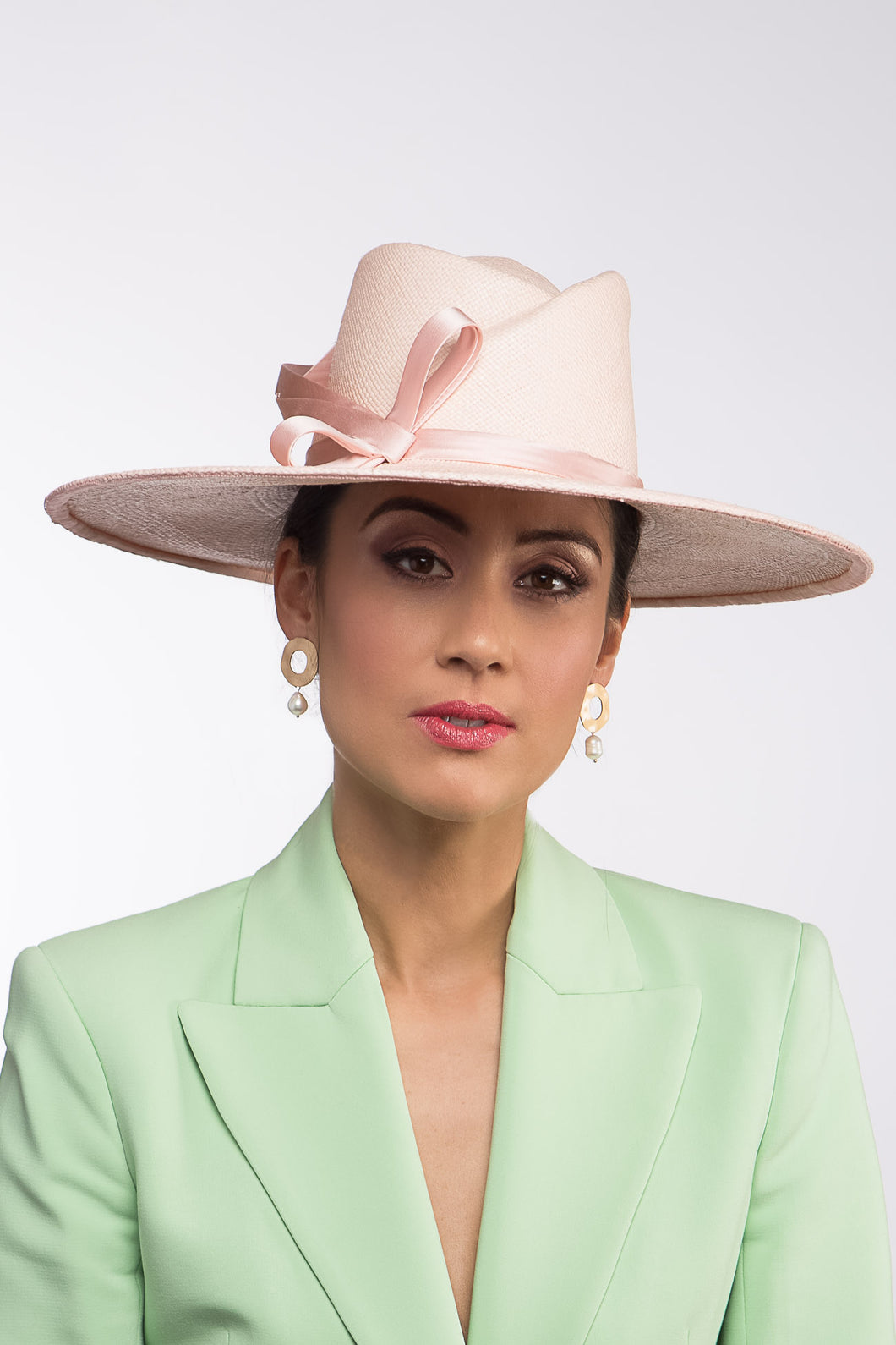 The Pink Panama Fedora with Silk Bow is a modern fedora with a sweeping angular crown and a wide flat brim in pastel pink straw