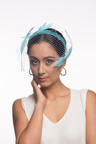 The Veiled Feather Leaf Headband in Blues features a birdcage veil adorned with feather leaves. The sky blue feather leaves are arranged over the pale blue ones