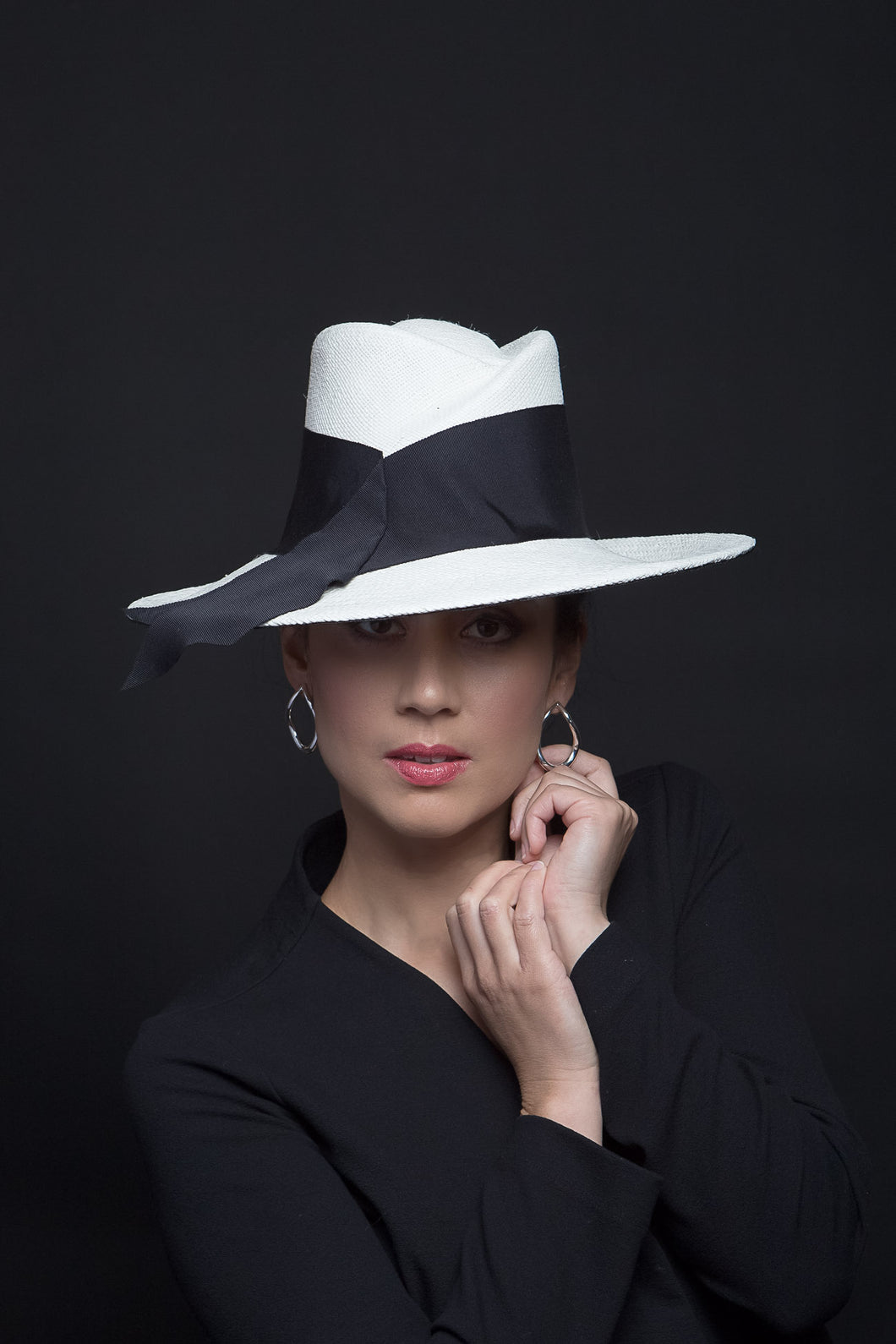 The White Panama Fedora with Black Trim is a modern fedora with a sweeping angular crown and features a wide brim which softly curves up.