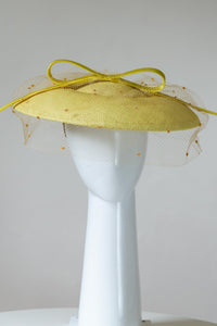 The Yellow Platter Hat with Bow and Veiling features a wide Dior brim with a shallow crown. Trimmed with a lux satin silk bow on across the brim and draped in a fine vintage veiling