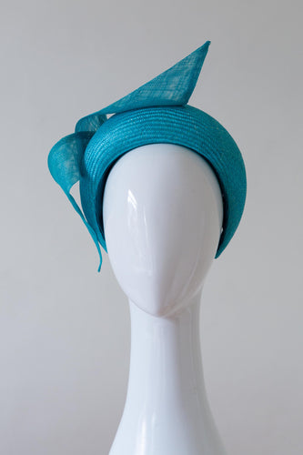The Sky Blue Halo headband with Sweeping Wave features a parisisal straw headband trimmed with a floating sinamay waves.