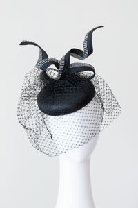 The black cocktail button hat with Monochrome Bow is covered in a fine vintage fabric, trimmed with a black and white bow and draped in black veiling